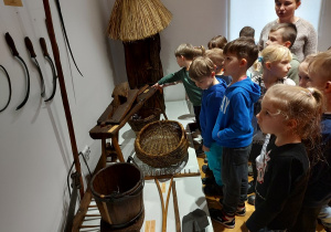 Dzieci oglądają narzędzia rolnicze z XIX wieku