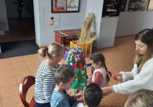 Przedszkolaki ozdabiają sukienkę Marzanny kolorowymi rysunkami