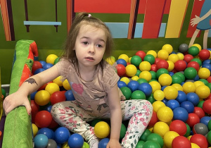 Dziewczynka siedzi na kolorowych piłeczkach