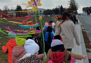 Dzieci niosące kolorowe dekoracje wracają do przedszkola z nauczycielkami