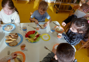 Dzieci smarują chleb masłem