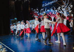 Dziewczynki i chłopcy tańczą z chustkami w barwach Polski