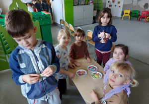 Dzieci robią bransoletki pod czujnym okiem starszych kolegów