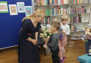 21. Chłopiec i dziewczynka wręczają kwiaty i laurkę pani Alinie.