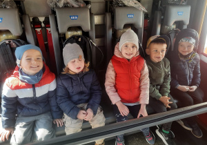 Dzieci siedzą w wozie strażackim