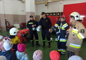 Nauczycielki i dzieci przymierzają stroje strażackie