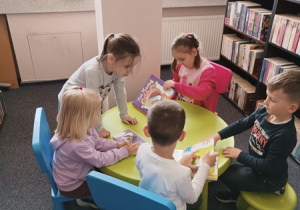 12. Dzieci oglądają książki w kąciku czytelniczym.