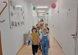Dzieci z misiem na krytarzu szkolnym