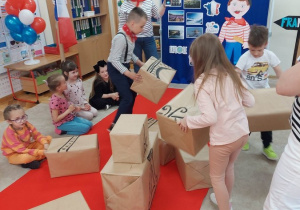 11 dzieci z grupy starszaków budują wieżę Eifla z pudełek