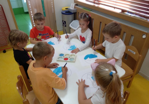 Dzieci malują farbami znaki drogowe.