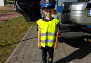 05 Chłopiec w czapce policjanta na tle radiowozu