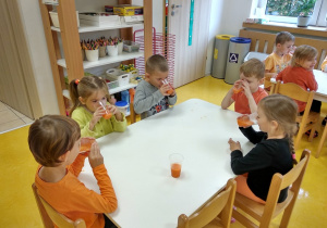 Dzieci piją sok zrobiony przez siebie.