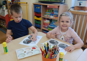 Dzieci przy stoliku malują palcami kropki