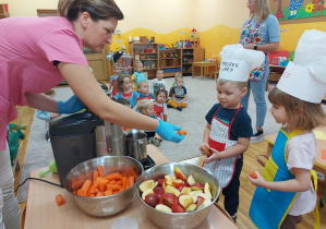 Przedszkolaki wrzucają owoce i warzywa do sokowirówki