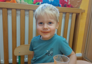 Chłopiec ma pomarańczowe wąsy po degustacji soku