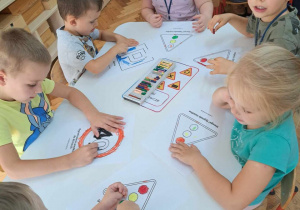 Dzieci podczas pracy przy stolikach - malowanie pastelami wg wzoru.