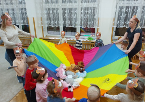 Dzieci huśtają misie na kolorowej chuście