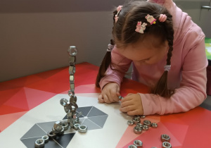 Dziewczynka układa wieżę z magnetycznych śrubek