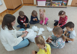 12 Dzieci z panią wypełniają pluszowe ciasteczka na dywanie
