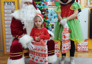 Zdjęcie dziewczynki z Mikołajem i Myszką MIki przy choince