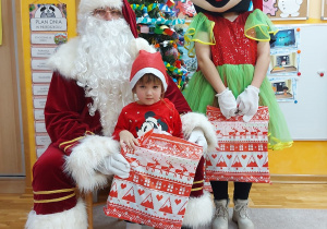 Zdjęcie dziewczynki z Mikołajem i Myszką MIki przy choince