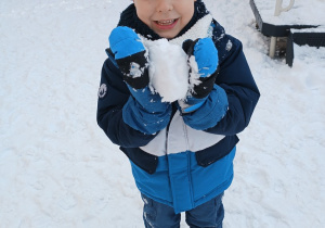Chłopiec trzyma śnieżną kulkę