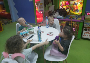 Dzieci siedzą przy stole i jedzą przekąski