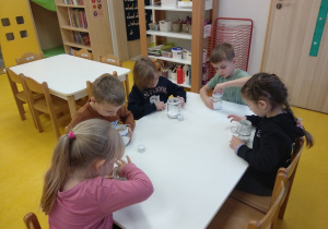 Dzieci przygotowują słoiczki ze świeczką.