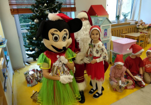 Zadowolona dziewczynka ze swoim prezentem i Mikołajem.
