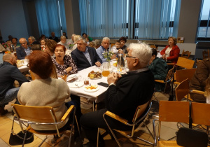 34 Babcie i dziadkowie siedzą przy stołach i częstują się ciastem i piją herbatę