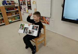Chłopiec pokazuje album i opowiada co przedstawiają zdjęcia.