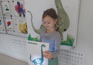 Dziewczynka wie czym się żywi przedstawiony na obrazku dinozaur.