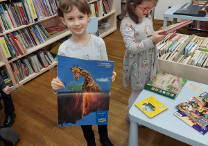 Dziewczynka prezentuje atlas ze zwierzętami świata.