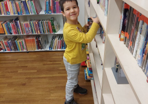 Chłopiec przegląda książki dla najmłodszych czytelników.