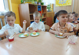 Dzieci jedzą deserki i babeczki