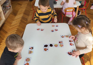 16 Przedszkolaki podzielone na grupy układają domino, kolorują kwiaty