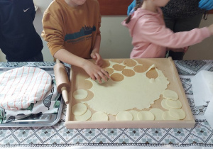 30. Chłopiec wykrawa ciasto na pierogi.