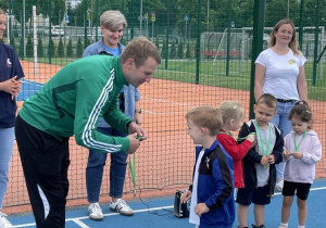 Zaproszony sportowiec wręcza medal chłopcu