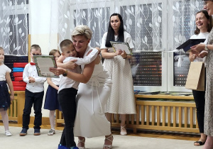 35. Chłopiec otrzymuje od pani dyrektor upominek.