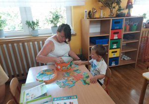 04. Chłopiec z mamą układa puzzle przy stoliku.