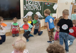Dzieci próbują utrzymać papierowe kropki pod brodą.