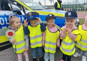 Przedszkolaki pozują do zdjęcia z atrubutami policjanta