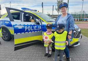 Przedszkolaki pozują do zdjęcia z atrubutami policjanta