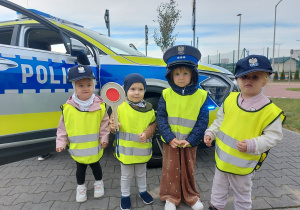 Przedszkolaki pozują do zdjęcia z atrubutami policjanta