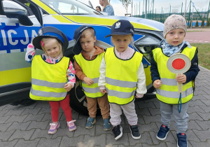 Przedszkolaki pozują do zdjęcia z atrubutami policjanta