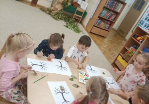 Dzieci malują liście farbami.