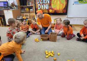 Dzieci z nauczycielem przeliczają znalezione pestki