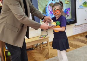 Dziewczynka odbiera nagrodę od Pani Dyrektor