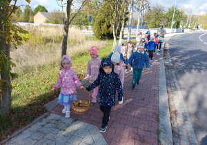 Pzredszkolaki z koszykiem wypełnionym darami jesieni wracają ze spaceru