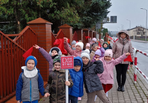 Dzieci z grupy Słoneczka podczas spaceru z napisem Dzieciństwo bez przemocy.